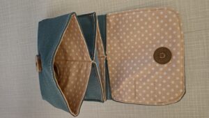 A képen egy apró pénztárca látható, ami mágneszárral csukódik, az elekén lehajtható fülön. kívül sötétzöld, belül világosbarna aprópöttyös anyagból van. 3 rekesze van, az elsőben aprópénz, a középsőben félbehajtott papírpénz, a leghátsóban bankkártya