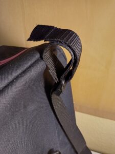 Ez egy olyan roller táska, ami nemcsak a kormány vízszintes részéhez rögzül, de a függőleges tengelyhez is. a járműről levéve hátizsákként használható. A táska maga és a pántok fekete színűek, a cipzárak rózsaszínűek. Elöl két kiálló zsebe van, alul mélyebb, fölül kicsit keskenyebb. A képen a fölső rögzítés látszik