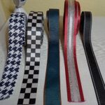 a képen táska pántokat, hevdereket látunk fekete-fehér lúdláb mintával, mellette fekete-fehér pepita mintával, mellette sötétbarna szélű sötétkék színben, mellette bordó szélű befelé ezüst, fehér csíkos, mellette fekete színű, ezüst fényvisszaverő csíkkal