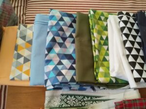 A képen pamut anyagok vannak szín szerint párosítva. fekete-fehér háromszög mintás mellett fehér, zöld háromszög mintás mellett egyszínű zöld, ugyanígy kék és barack színű mintás és egyszínű anyagok