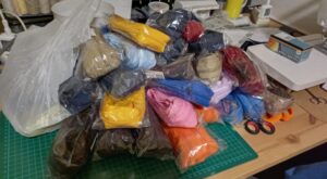 A képen a varrógép mellett egy nagy halom színes cipzár. nagyon sok :)